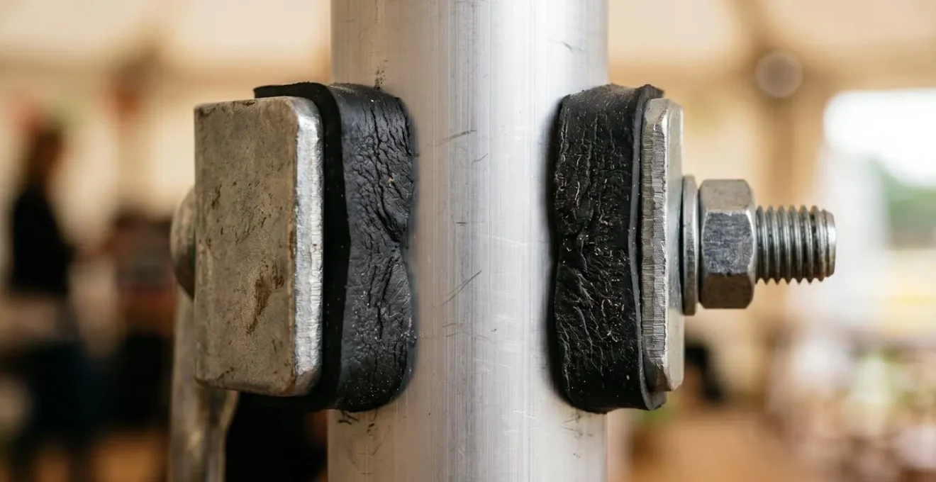 Close-up detail of protective padding between metal clamp and marquee pole showing proper damage prevention technique