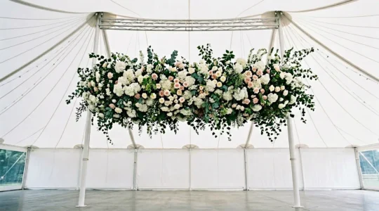 Gravity-defying suspended floral cloud hovering above marquee wedding setup with elegant rigging structure